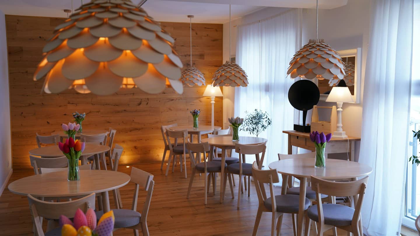 Tavoli e sedie in legno disposti all'interno di un luminoso caffè moderno.