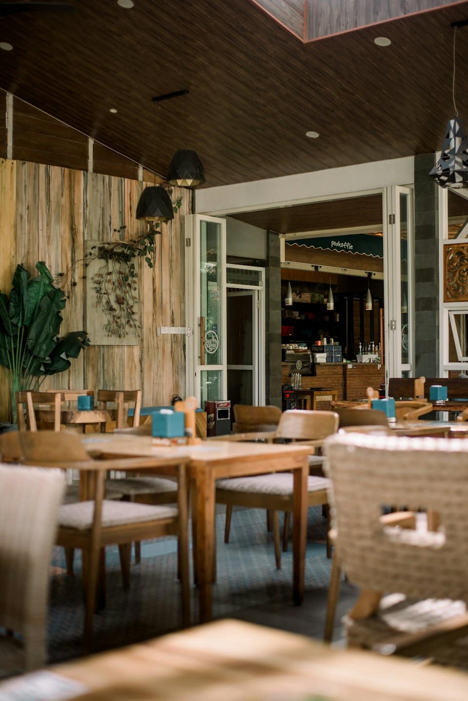 Interno di un caffè vuoto con tavoli e sedie di legno.