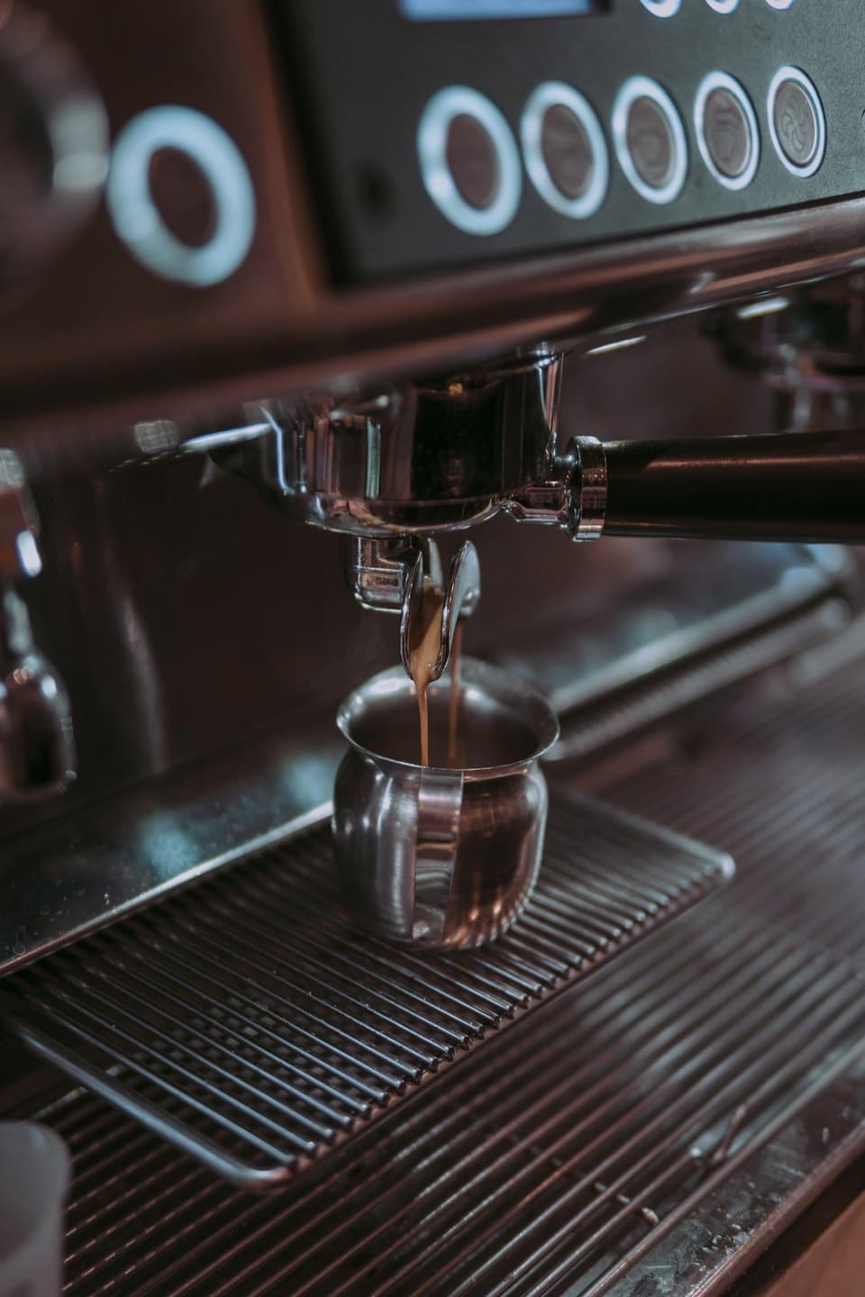 Il caffè espresso cola da un portafiltro in una tazzina di metallo.