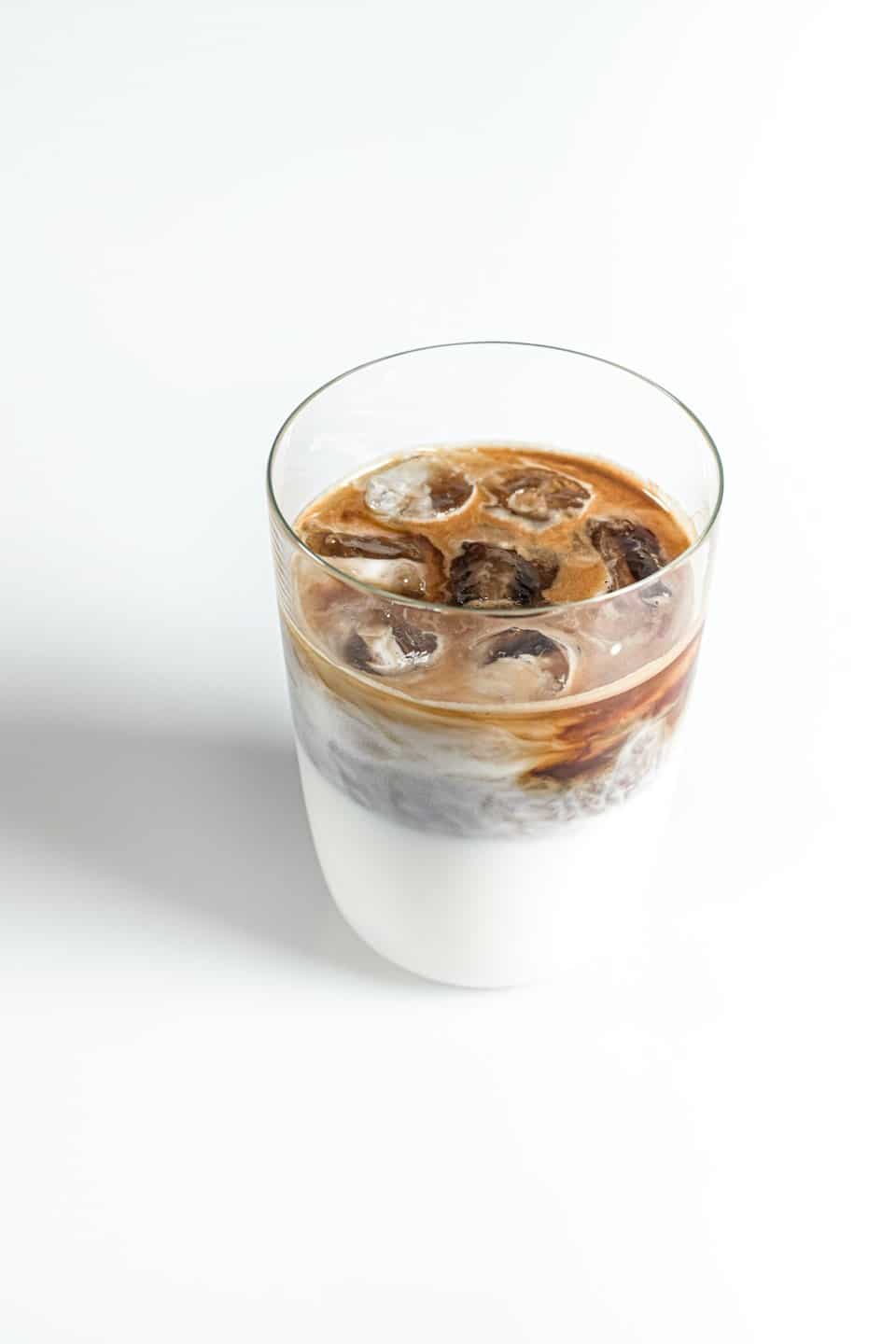 Caffè freddo stratificato in un bicchiere trasparente con cubetti di ghiaccio.