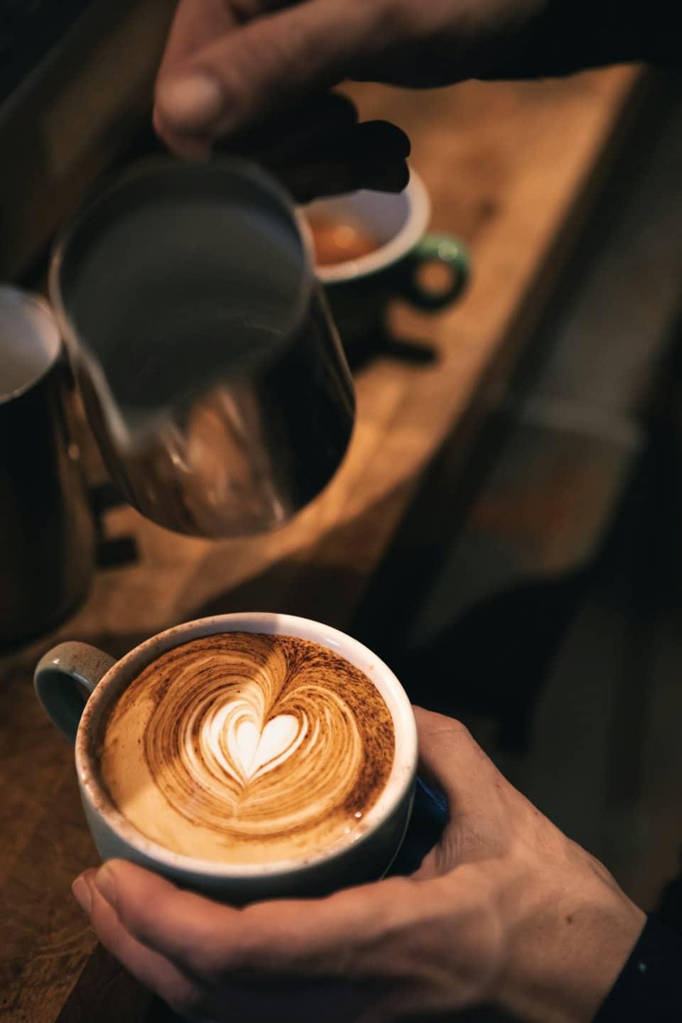 Un barista versa latte montato in una tazza di caffè.
